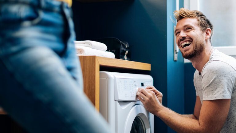Linge propre : ces trois détergents suffisent 3 Homme riant devant la machine à laver