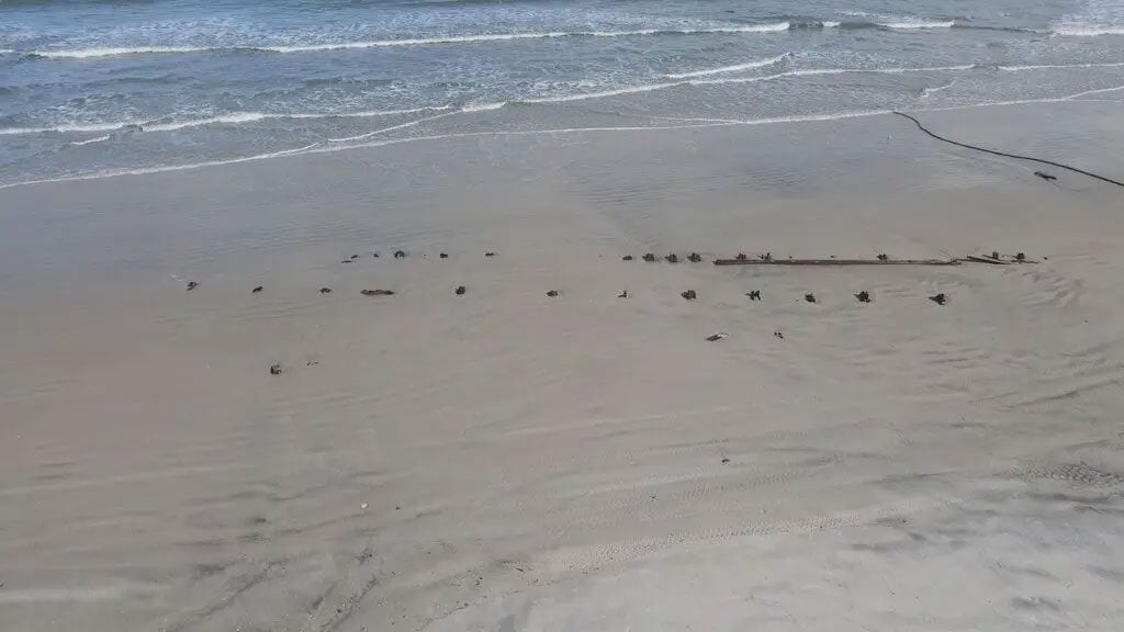 "Voici ce qui est caché dans le sable": résolu le mystère de l'objet refait surface en Floride 3 Vue aérienne de l'objet émergeant du sable / Daytona Beach Shores