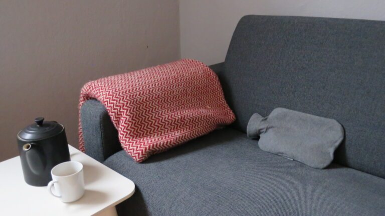 Canapé avec couverture, bouillotte et thé chaud Canapé avec couverture, bouillotte et thé chaud