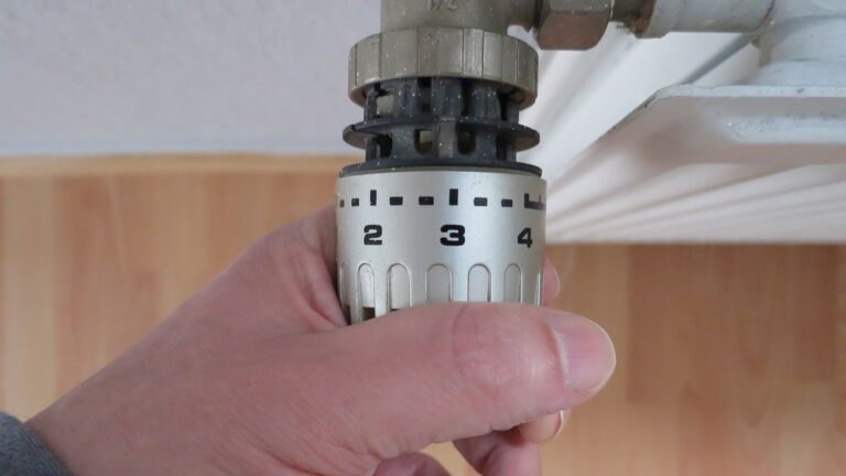 Main sur le thermostat du radiateur Main sur le thermostat du radiateur