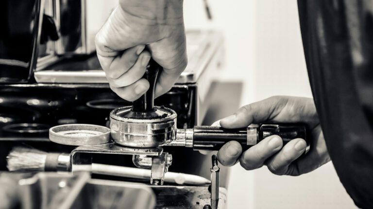 Barista en train de compacter la mouture de café pour le porte-filtre