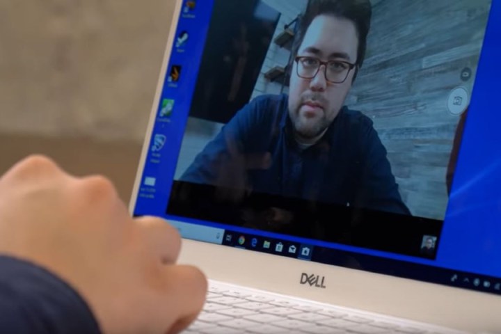 Gros plan d'une personne utilisant un ordinateur Dell avec sa caméra allumée. L'image de la personne est visible sur l'écran de l'ordinateur.