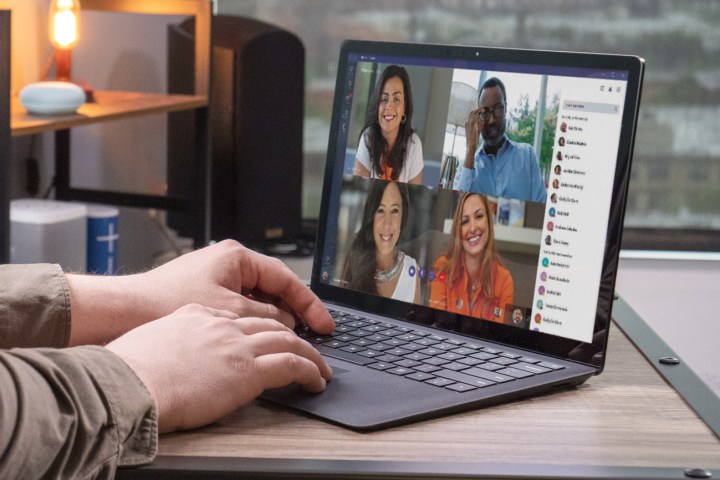 Gros plan sur les mains d'une personne sur le clavier d'un ordinateur portable lors d'un appel vidéo groupé.