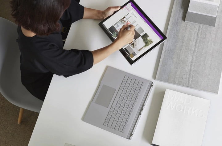 Vue de dessus d'une personne utilisant un ordinateur portable 2-en-1 en mode tablette tout en étant assise à un bureau blanc.