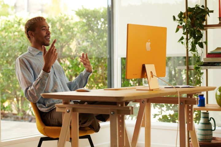 Un homme assis à un bureau devant un iMac M1.