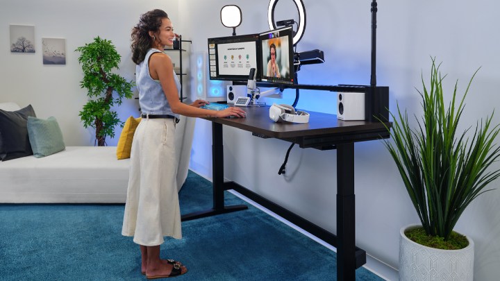 Votre bureau debout n'est peut-être pas si bon pour vous après tout 2 A woman stands at the Corsair Platform:6 desk as she participates in a video call.