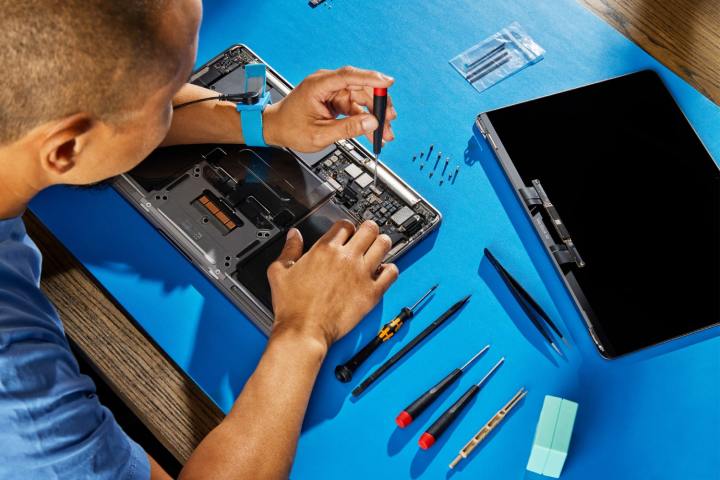 Qu'est-ce qu'AppleCare+ et vaut-il vraiment le coup d'être ajouté à votre MacBook ? 2 Une personne réparant un MacBook sur une table bleue.