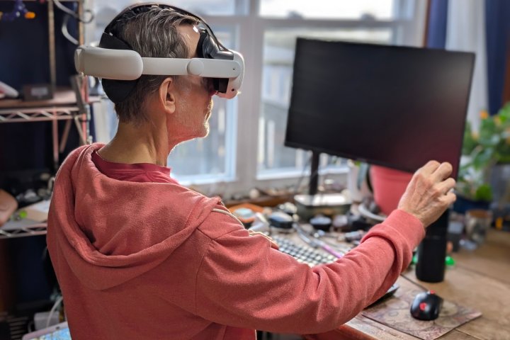 Les casques XR s'apprêtent à connaître une année décisive déterminante ! 6 Alan Truly sits in front of a Windows PC and adjusts a virtual screen while wearing a Meta Quest 3 VR headset.