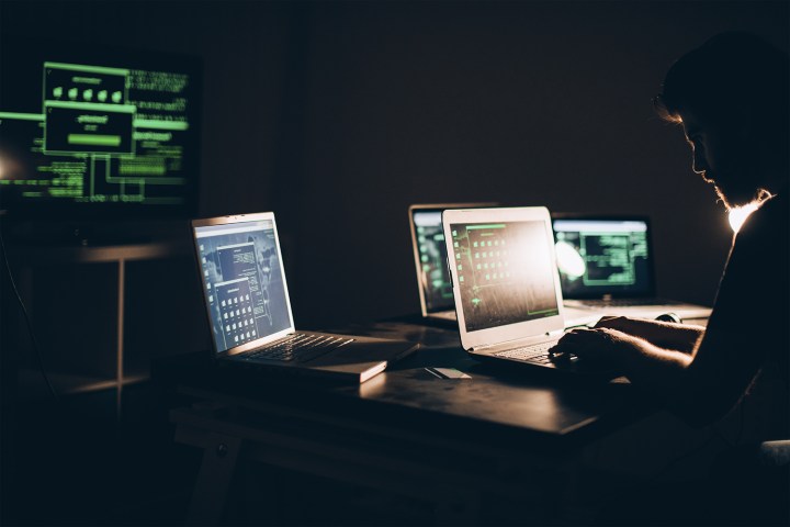Le FBI s'apprête à éliminer ce malware nuisible qui a touché 2,5 millions d'ordinateurs ! 2 Une personne entourée de plusieurs ordinateurs tapant sur un ordinateur portable.