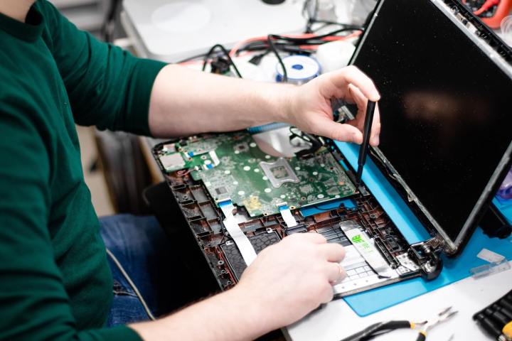 Un nouveau rapport critique la réparabilité des MacBooks. Voici ce que vous pouvez faire si vous devez réparer le vôtre 5 Une personne réparant l'intérieur d'un MacBook avec un petit tournevis.