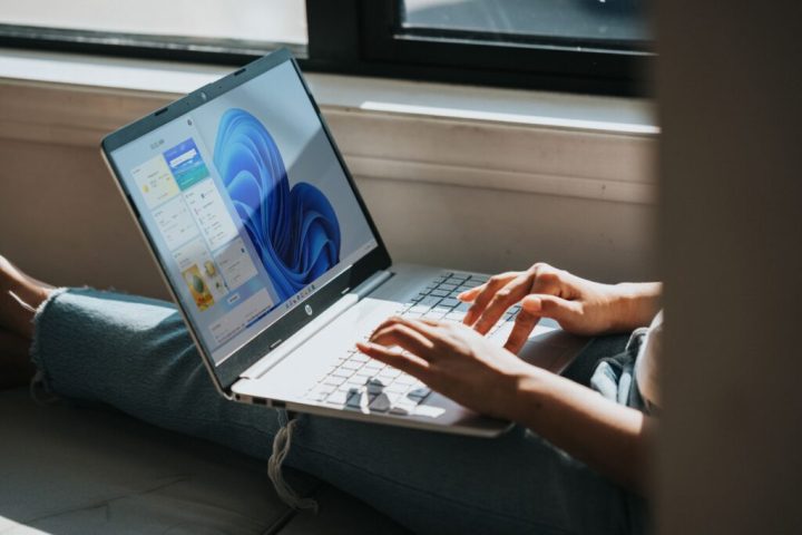 Personne utilisant un ordinateur portable Windows 11 sur ses genoux près de la fenêtre.