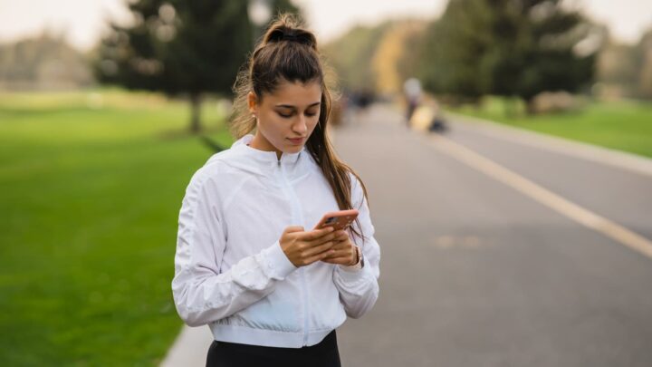 Il n'est pas trop tard : 5 applications de course pour dépasser le simple comptage des kilomètres 3 Jeune femme avec smartphone en tenue de course