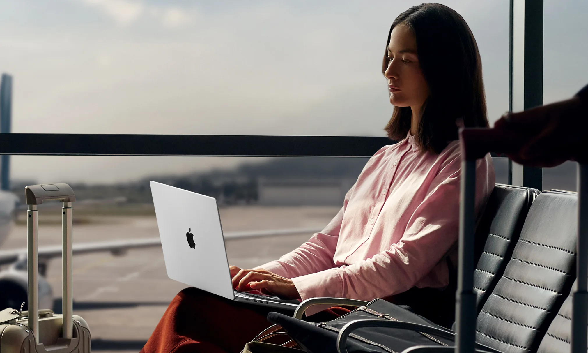 Des modèles de MacBook Pro avec des puces M5 encore plus puissantes pourraient bientôt arriver 3 Le MacBook Pro 14 M5 d'Apple sur les genoux d'une femme à l'aéroport.