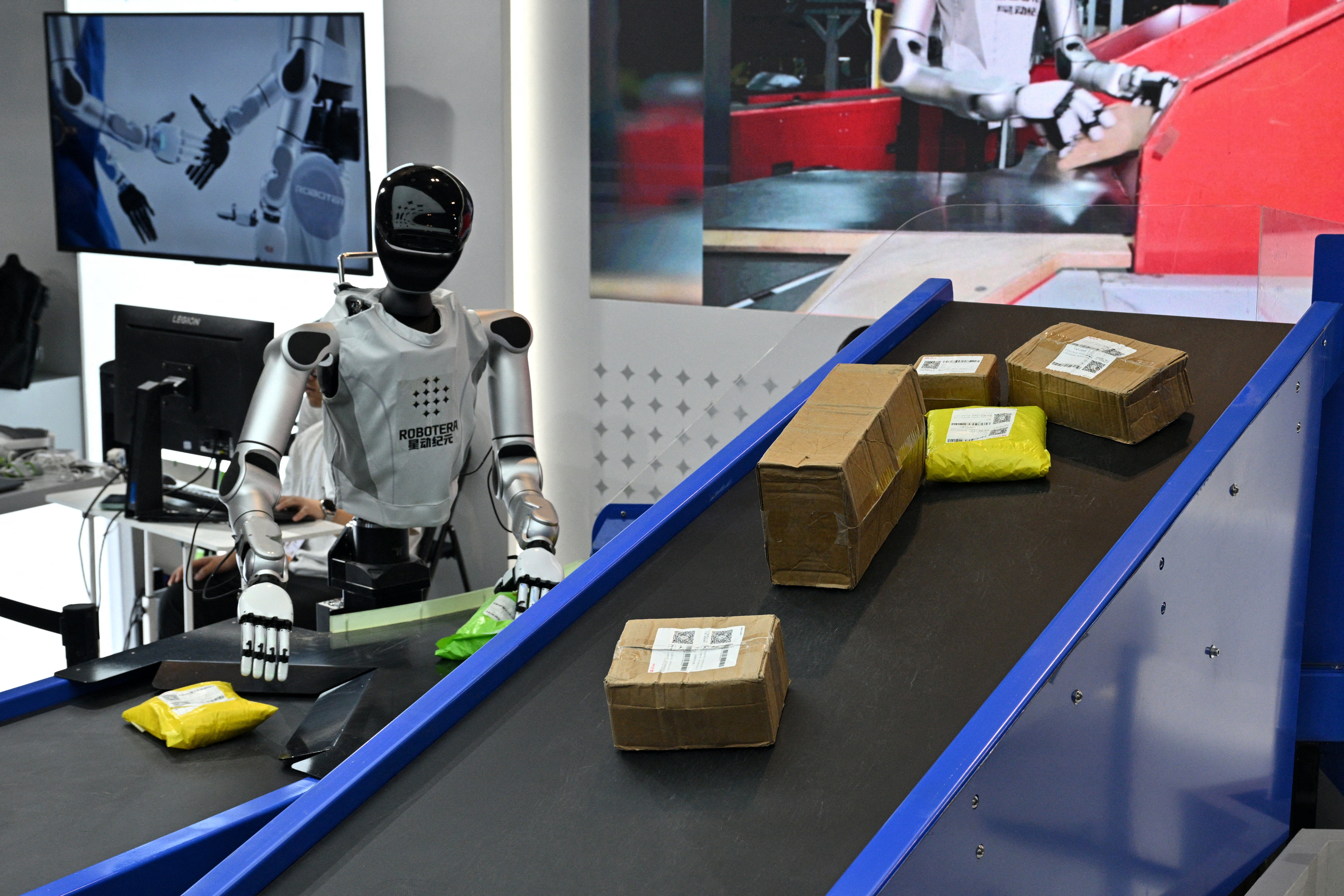 Un robot humanoïde de Robotera travaille sur des colis pendant la World Artificial Intelligence Conference (WAIC) à Shanghai le 18 juillet 2026.