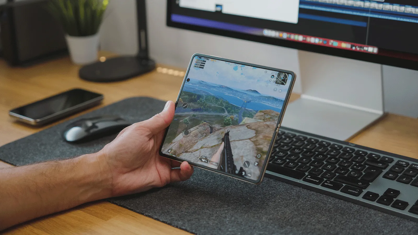 Les jeux mobiles les plus téléchargés sur Android et iOS 6 Gros plan d'une personne tenant le Honor Magic V5 ouvert tout en jouant à PUBG Mobile sur un bureau avec un ordinateur.