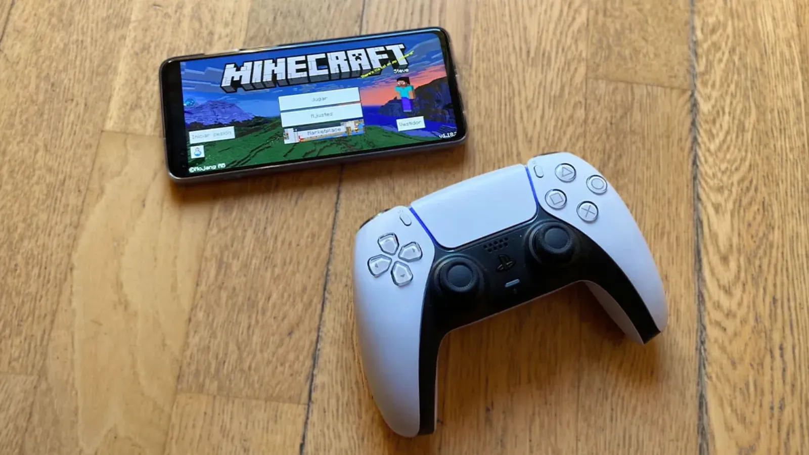 Les jeux mobiles les plus téléchargés sur Android et iOS 15 Manette DualSense de PS5 à côté d'un téléphone mobile affichant l'écran de démarrage de Minecraft sur un sol parqueté.