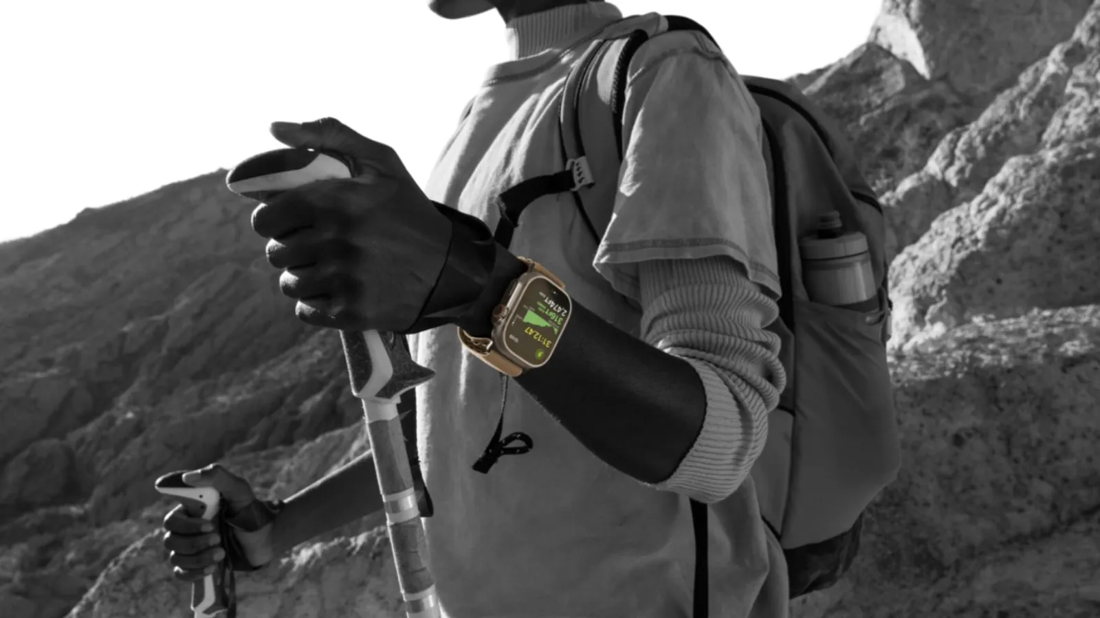 Toutes les versions de watchOS : l'évolution de l'Apple Watch au fil des ans 4 Gros plan d'une personne faisant de la randonnée avec un Apple Watch Ultra 4 au poignet tout en tenant des bâtons de marche.
