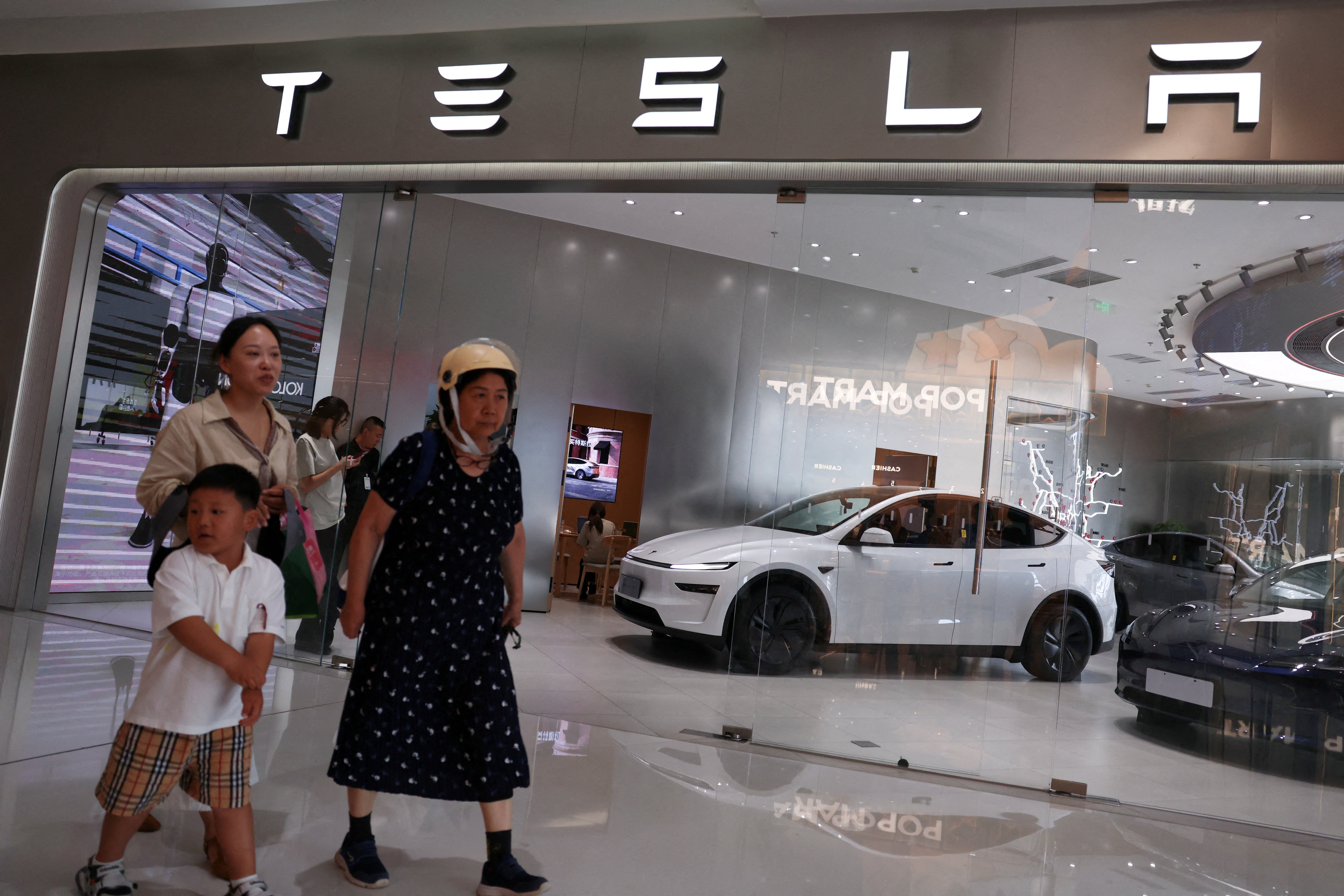 Des passants marchent devant une boutique Tesla dans un centre commercial de Pékin, en Chine, le 31 juillet 2026.
